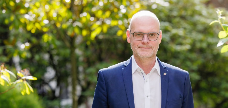 Hauptgeschäftsführer Christof Sommer vor einem mit Pflanzen bewachsenen Hintergrund.
