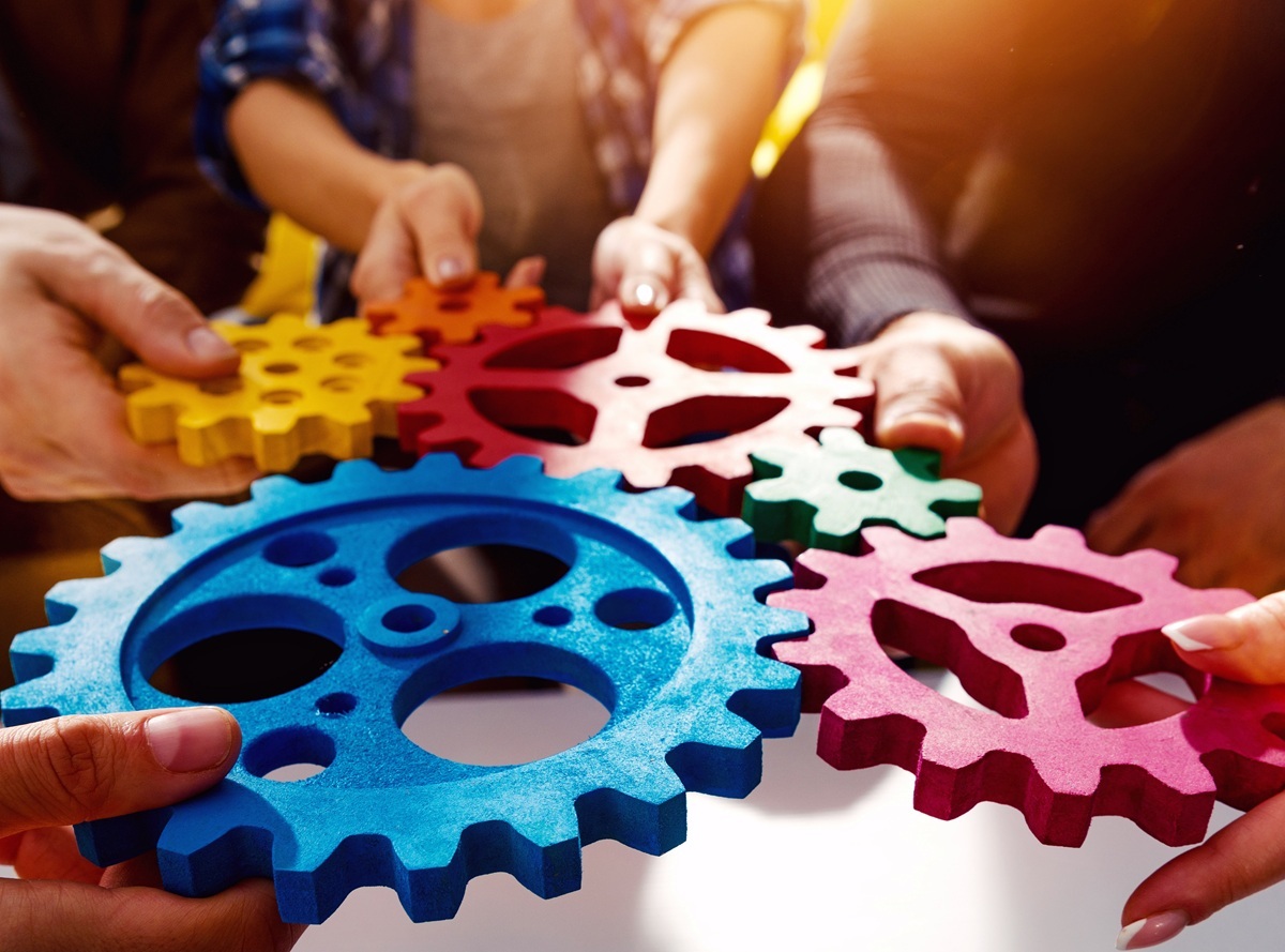 Hände halten Zahnräder ineinander, so dass eins in andere greift Hände halten Zahnräder ineinander, so dass eins in andere greift