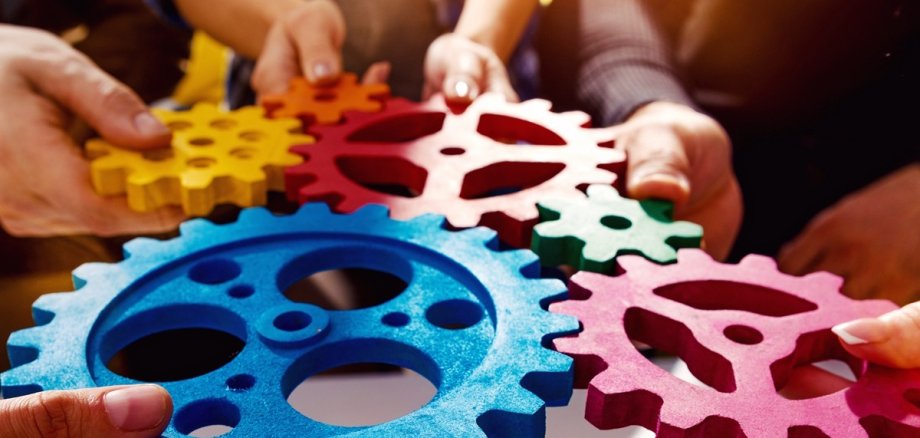 Hände halten Zahnräder ineinander, so dass eins in andere greift